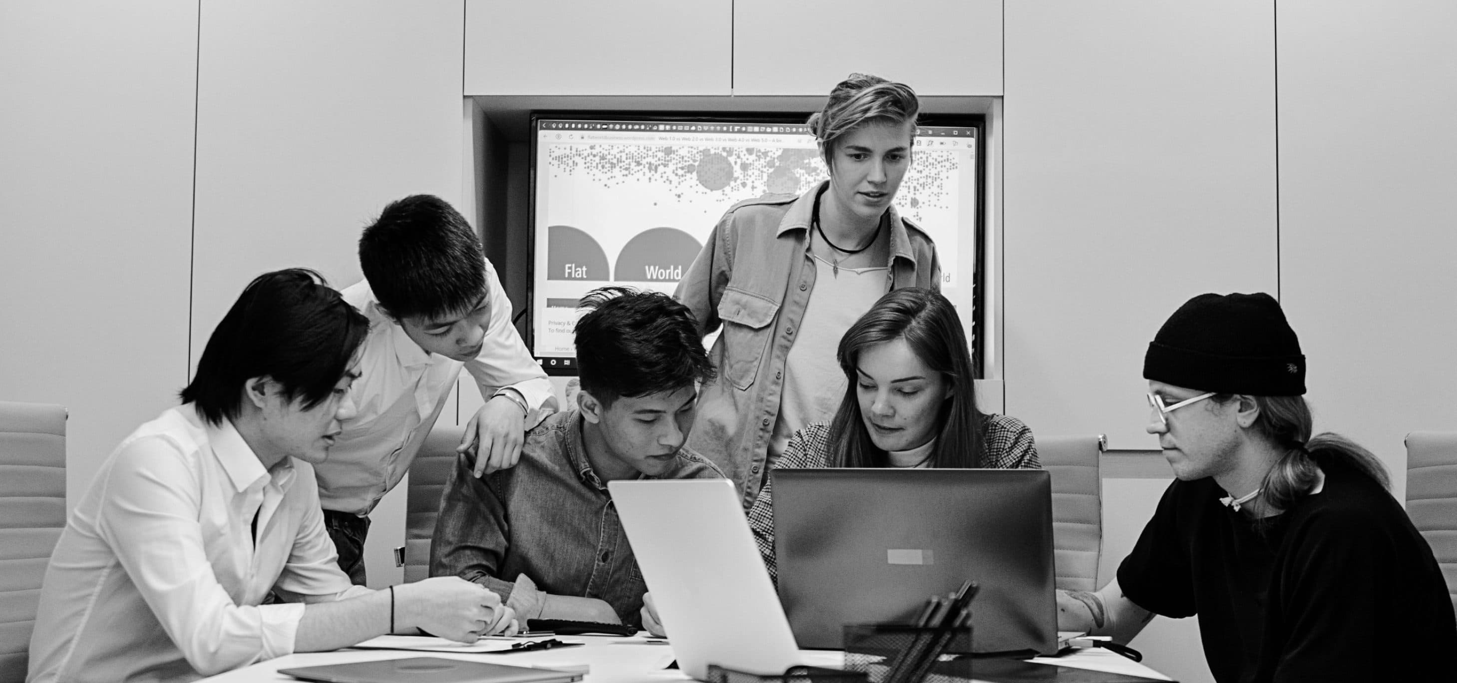 Équipe réunie autour d'une table de travail, plans et ordinateur portable